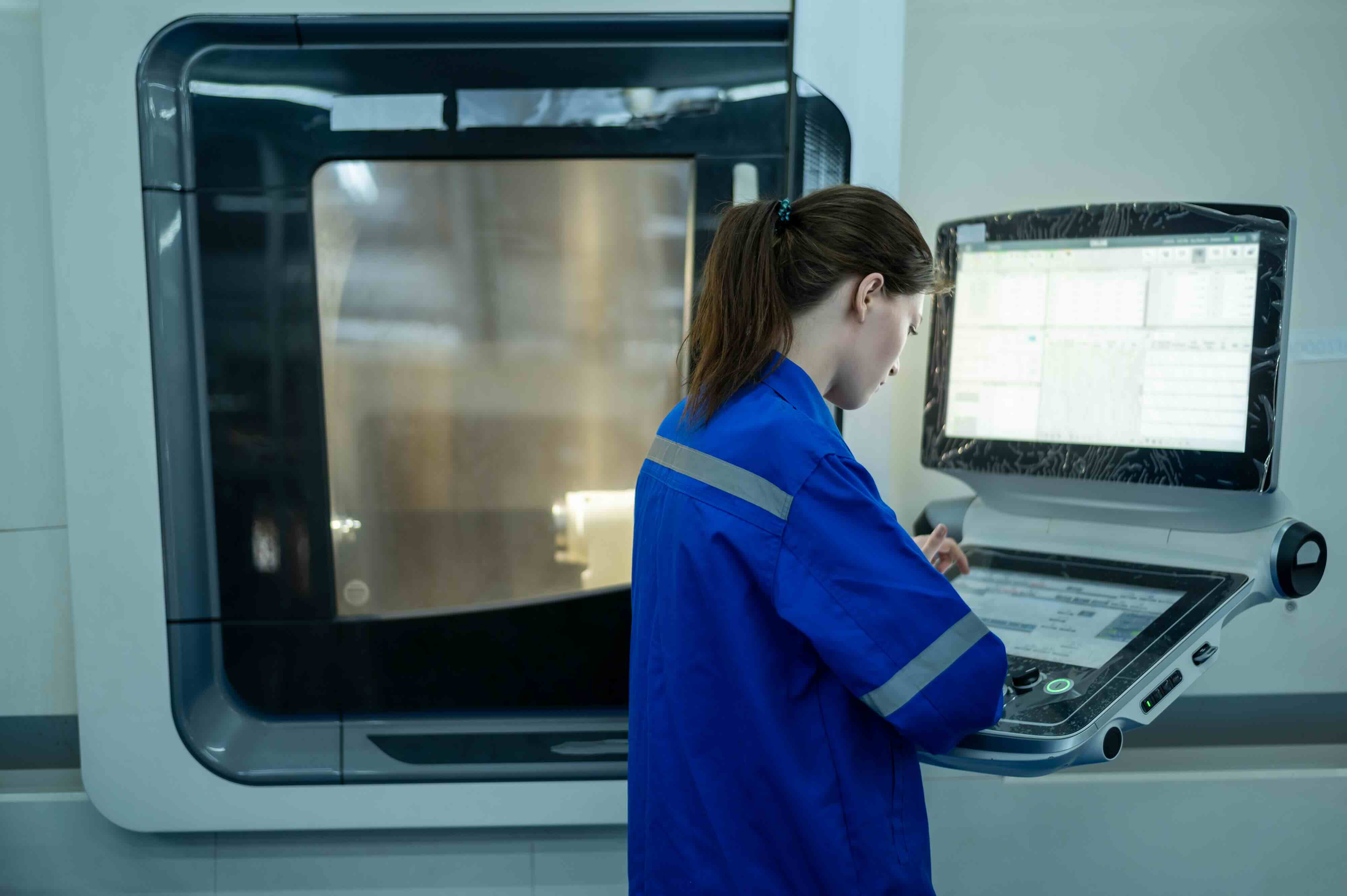 A technician operating heavy machinery in a modern manufacturing facility, representing how QReserve regulates equipment access control, enforces operator safety prerequisites, and monitors industrial asset utilization.