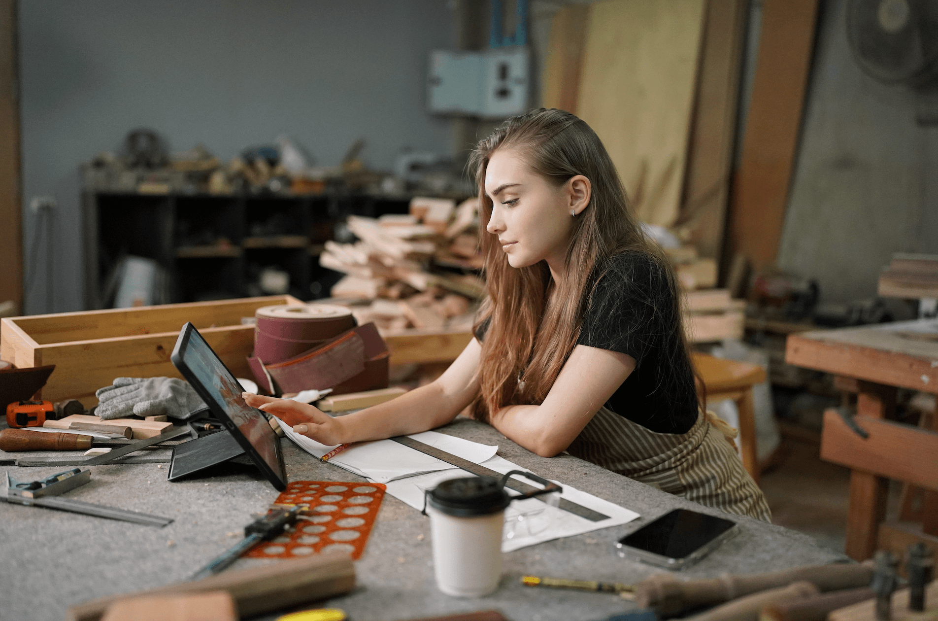 A user operating a mobile device in a makerspace, representing QReserve's kiosk check-in and safety certification verification.