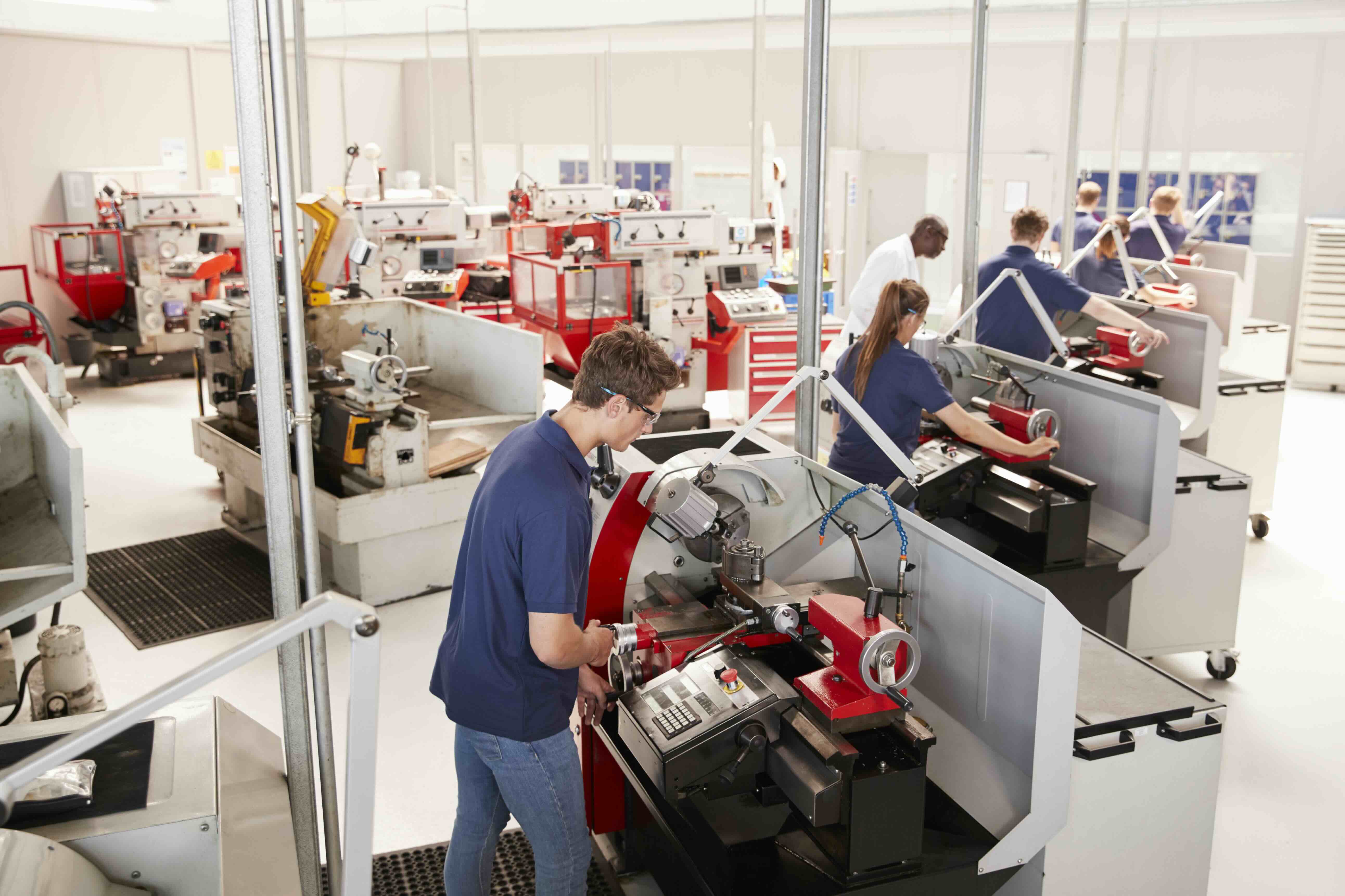Technicians and operators working with machinery in an industrial setting, representing how QReserve manages complex scheduling, maintenance tracking, and operator workflows for manufacturing and industrial facilities.