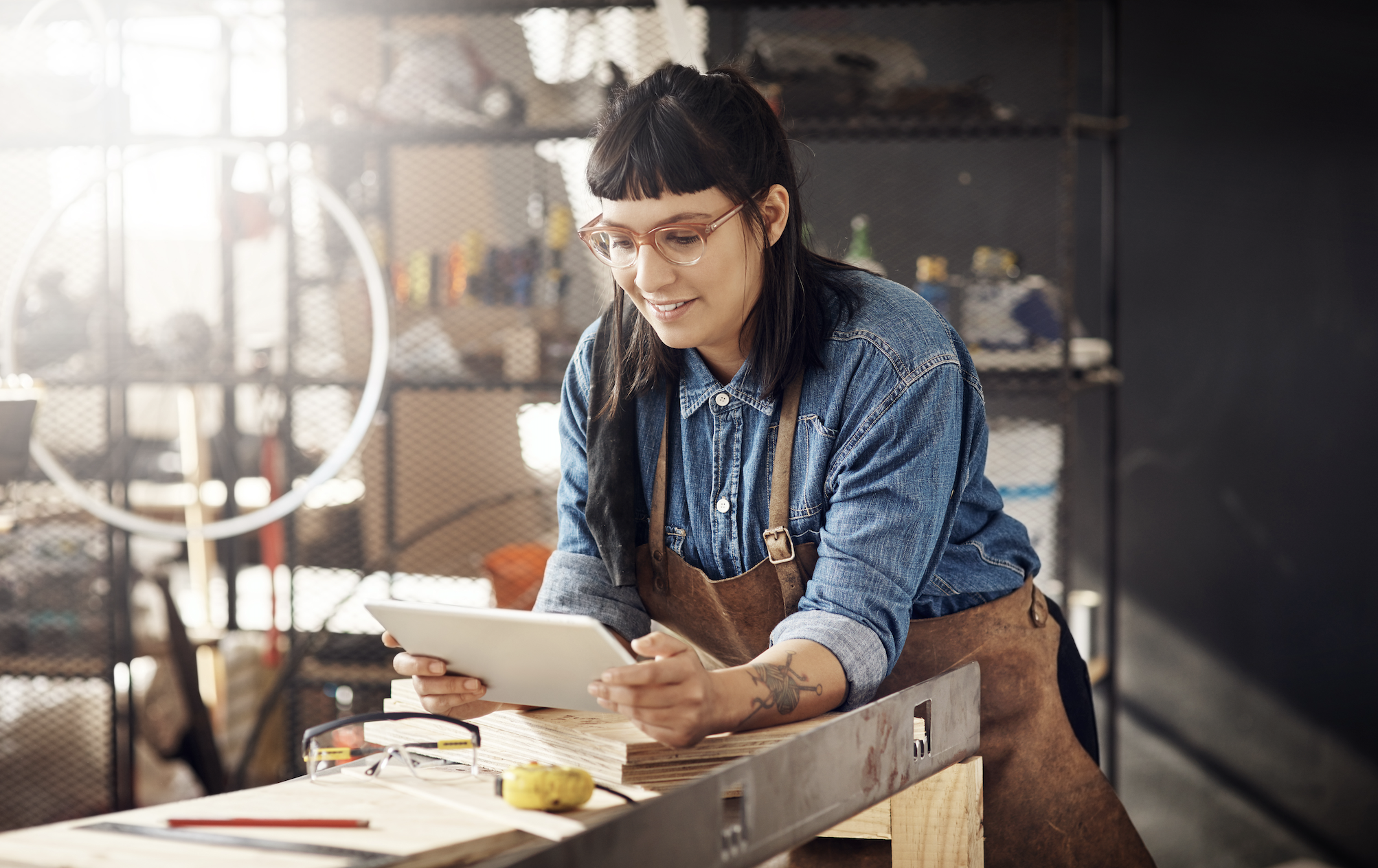 A woman using a tablet inside a workshop, representing QReserve’s mobile interface for managing tool reservations, checking equipment availability, and tracking usage in shared shop environments.